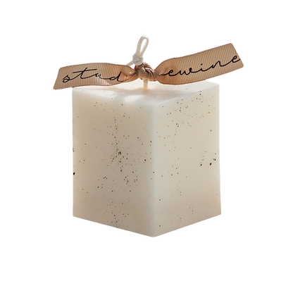 a dotted white square pillar candle with beige bluewine studio ribbon