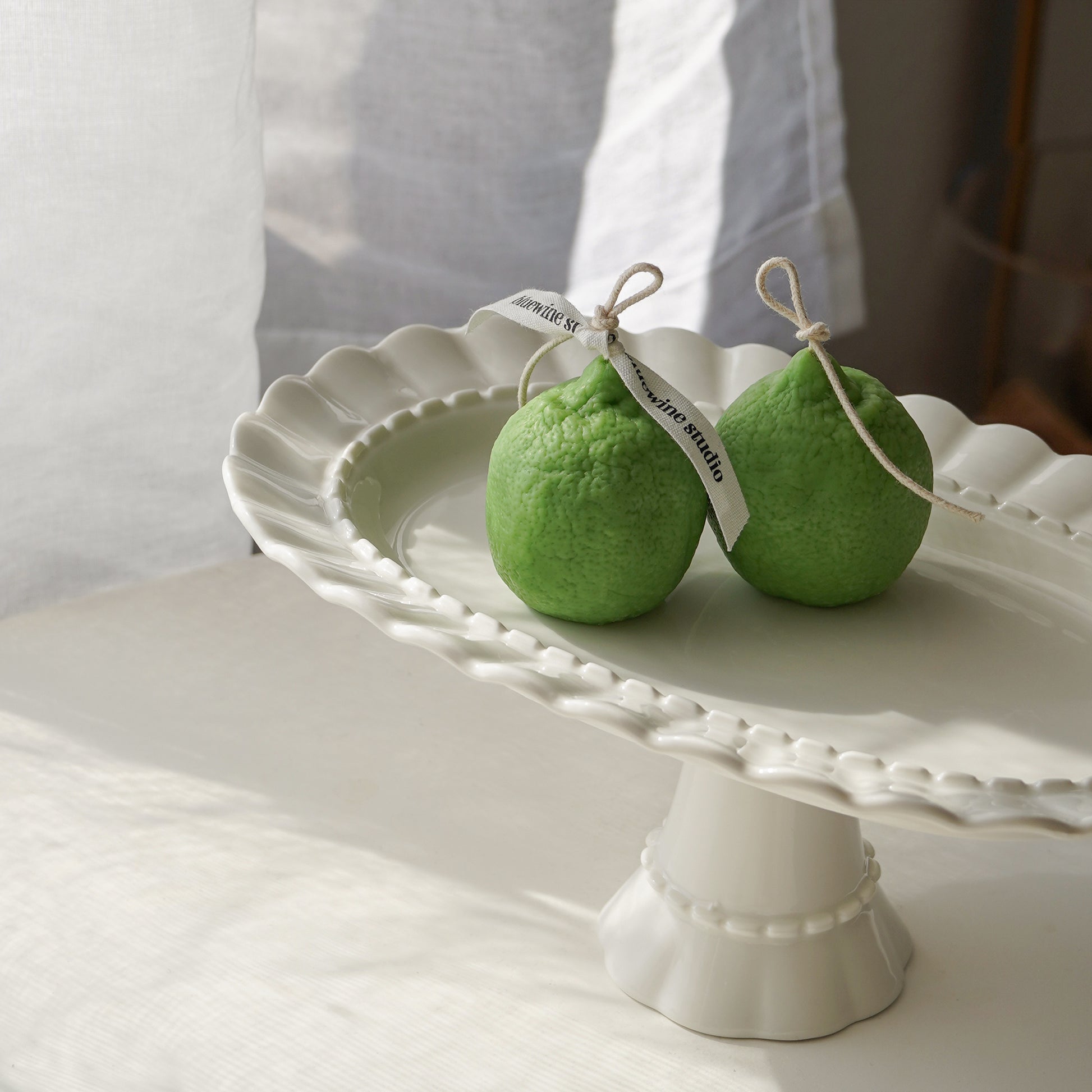 two lime-shaped candles placed on a white cake stand