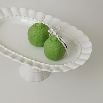 two lime-shaped candles placed on a white cake stand