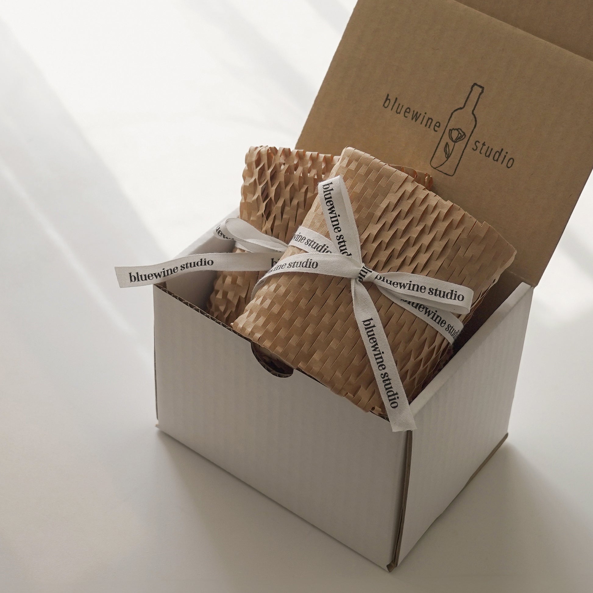 eco-friendly packaged item with honeycomb kraft paper and a white cotton ribbon in a white package box